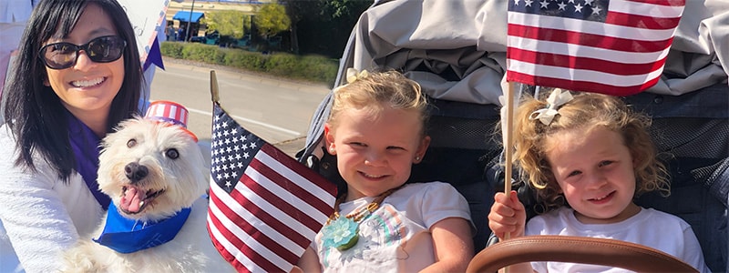 Smiling woman dog and child holding American flag.